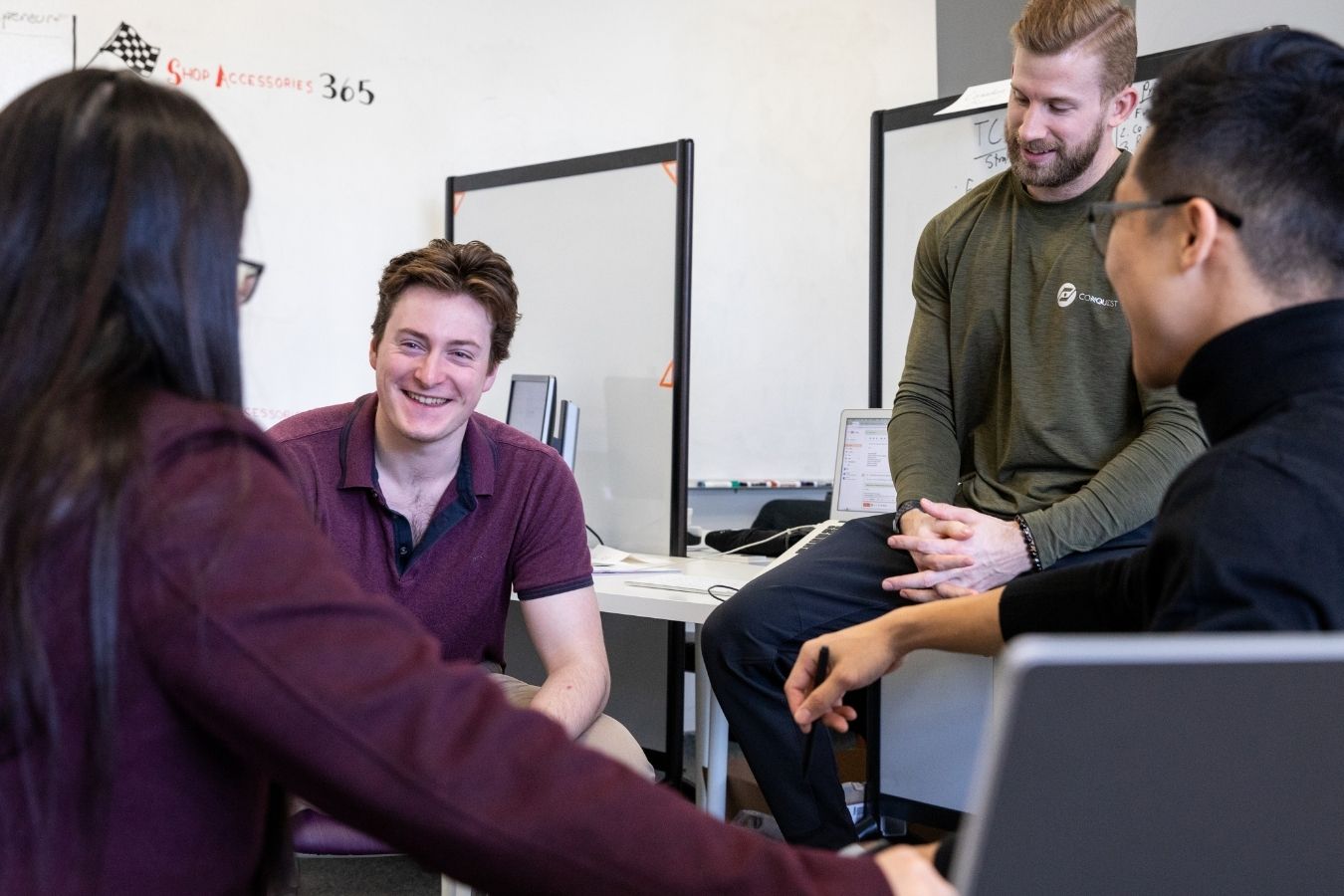 Group of entrepreneurs huddled in circle chatting and laughing